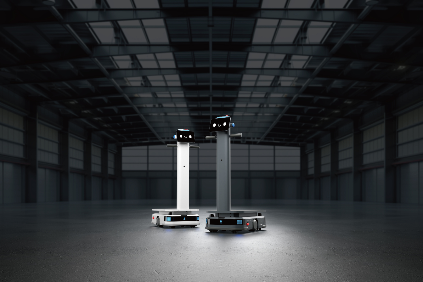Zwei autonome T300 Roboter in Weiß und Schwarz stehen nebeneinander in einer großen Industriehalle