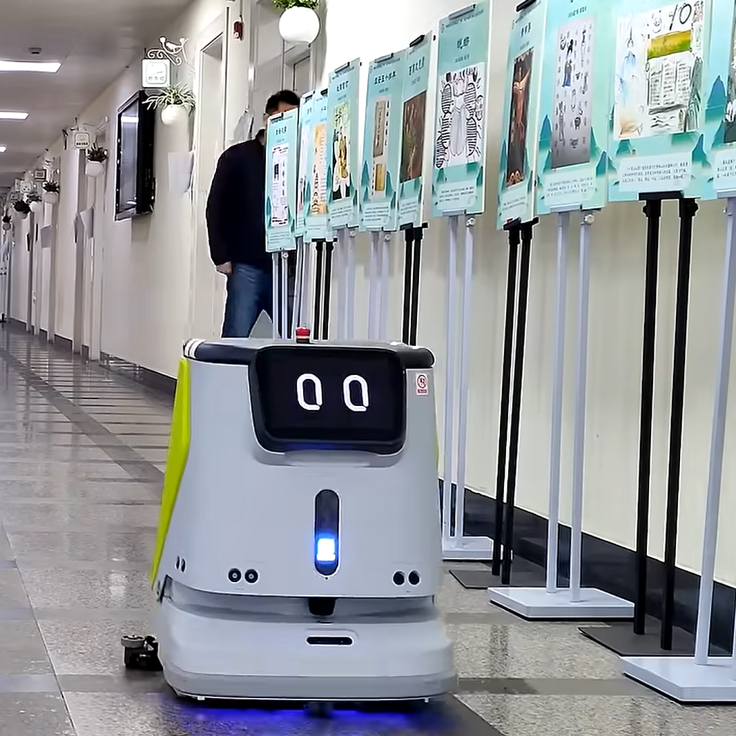 CC1 Reinigungsroboter fährt durch einen Schulflur mit Ausstellungsständern und Wanddekorationen