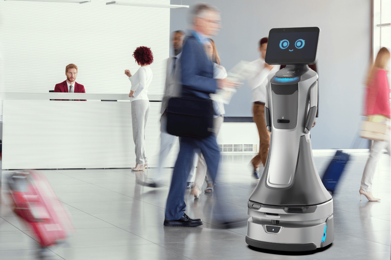 Empfangsroboter mit Display begrüßt Gäste in einer modernen Hotellobby mit laufenden Personen