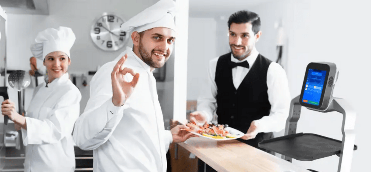 Köche und Kellner arbeiten gemeinsam mit Serviceroboter für effiziente Abläufe in der Küche