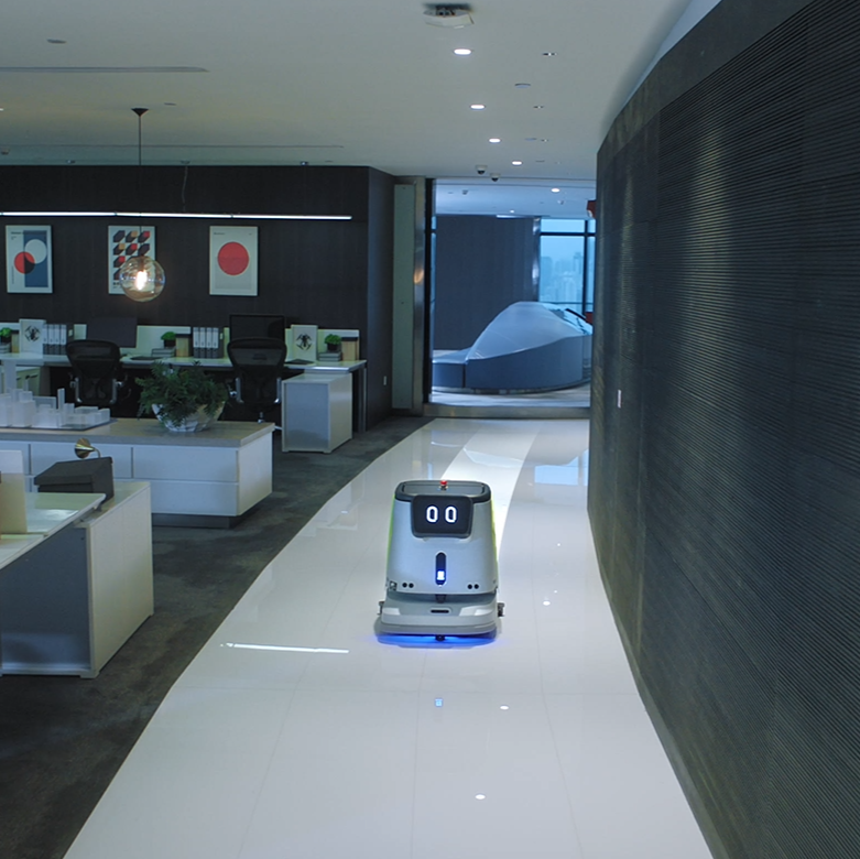 CC1 Reinigungsroboter fährt autonom durch modernes Büro mit dunklem Holz und Glasflächen