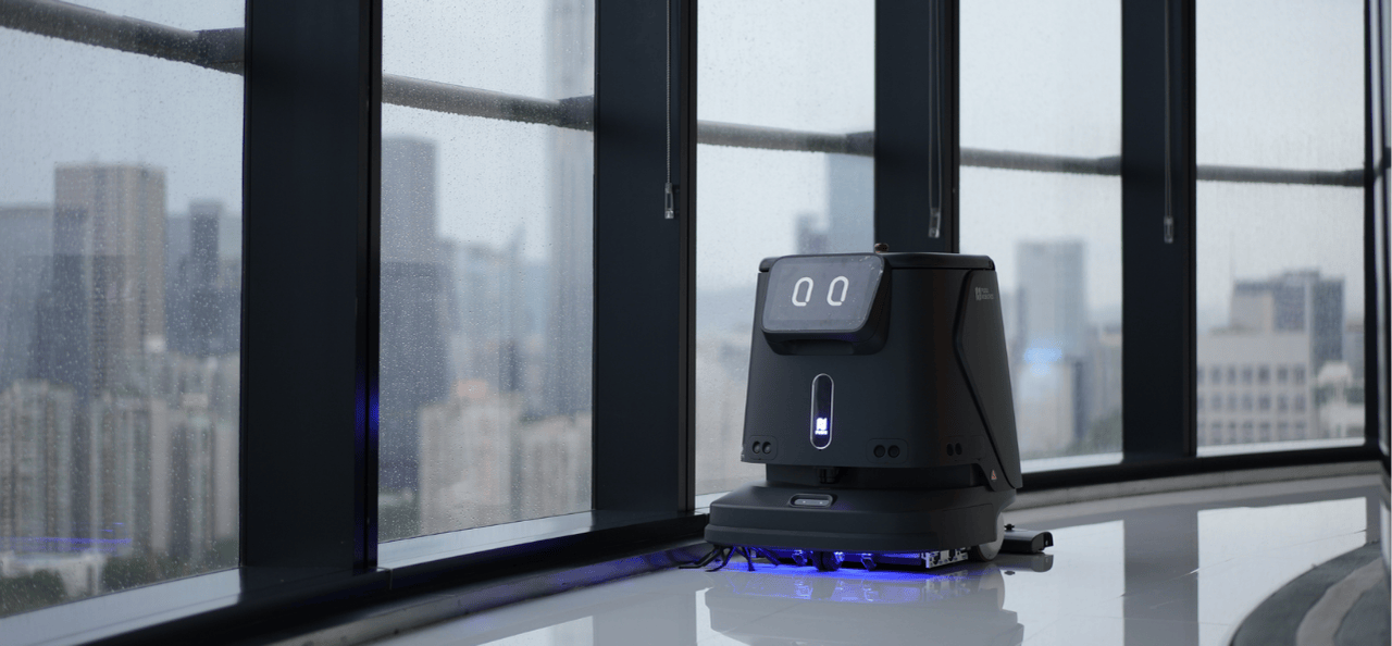 Schwarzer Reinigungsroboter fährt autonom an großen Panoramafenstern eines Hochhauses entlang